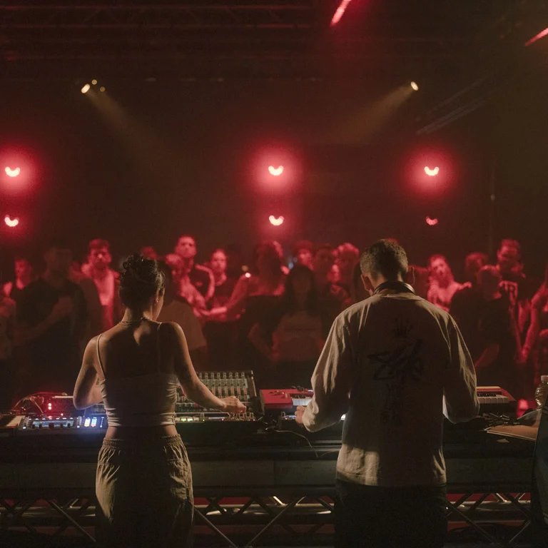 Zwei DJs in rotem Licht vor Publikum