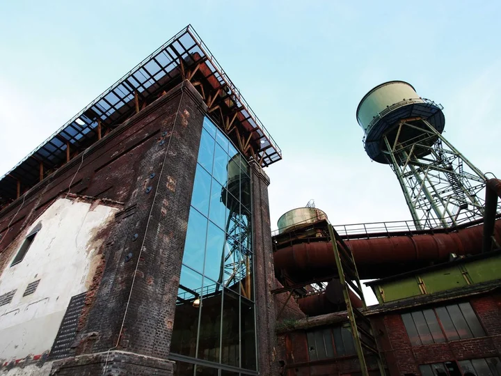 Außenansicht des Dampfgebläsehauses in Bochum, mit industriellen Details wie Rohren und einem Wasserturm, die sich gegen den blauen Himmel abheben.