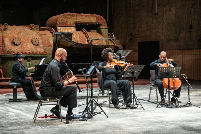 Yshani Perinpanayagam, Alexander Laing, Sarah Martin und Khari Joyner auf einer industriellen Bühne.