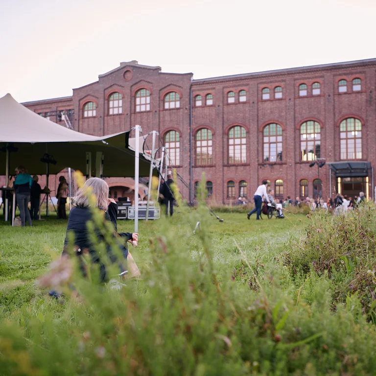 Die Maschinenhalle Zweckel in Gladbeck mit einer großen Backsteinfassade und begrüntem Außenbereich, im Abendlicht aufgenommen.